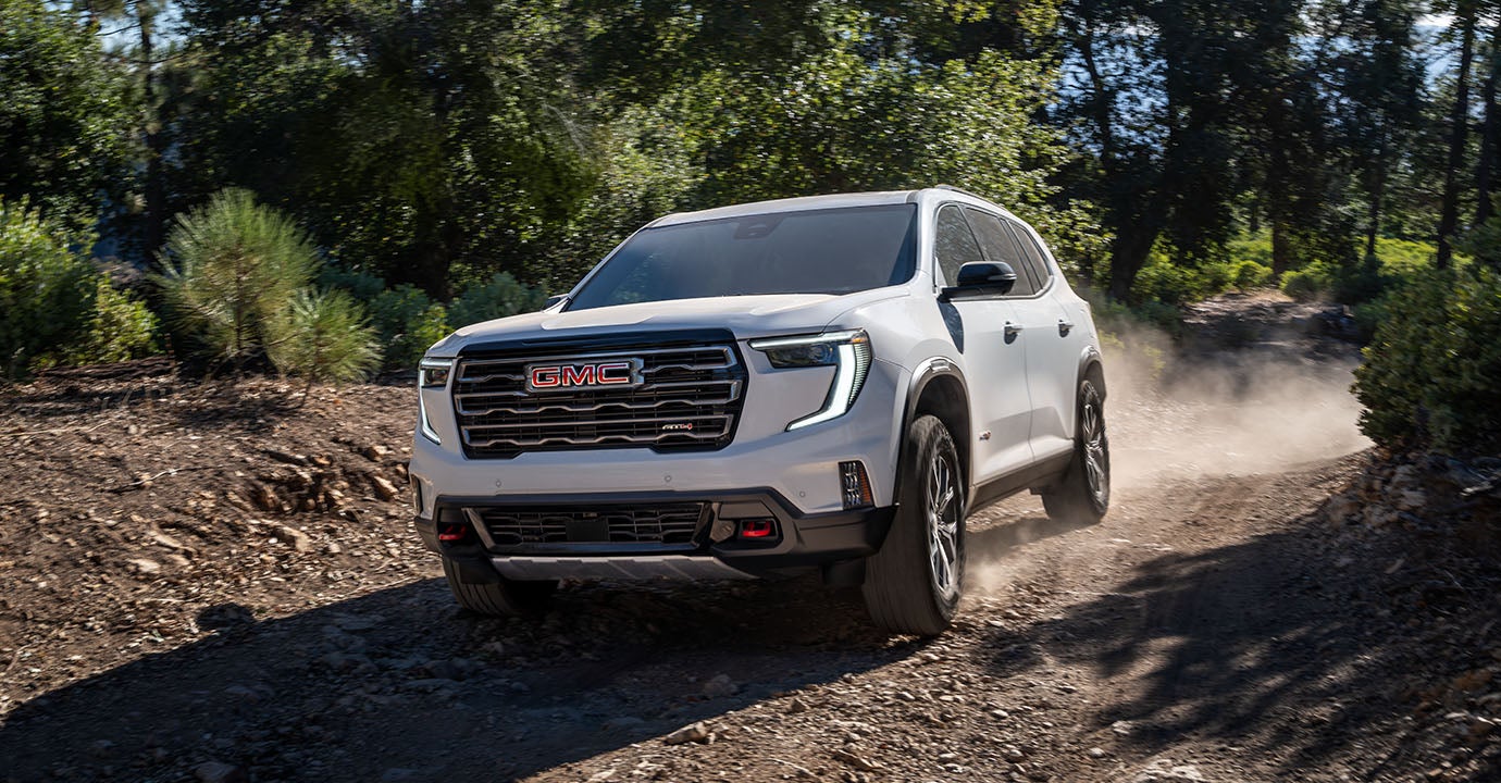 GMC Acadia AT4 driving on a forest trail.