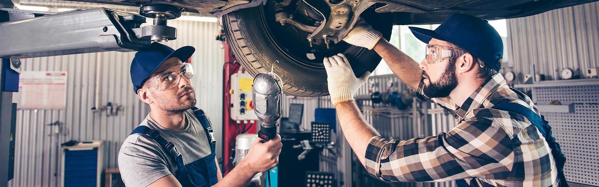 Auto technicians servicing a vehicle in a repair shop.